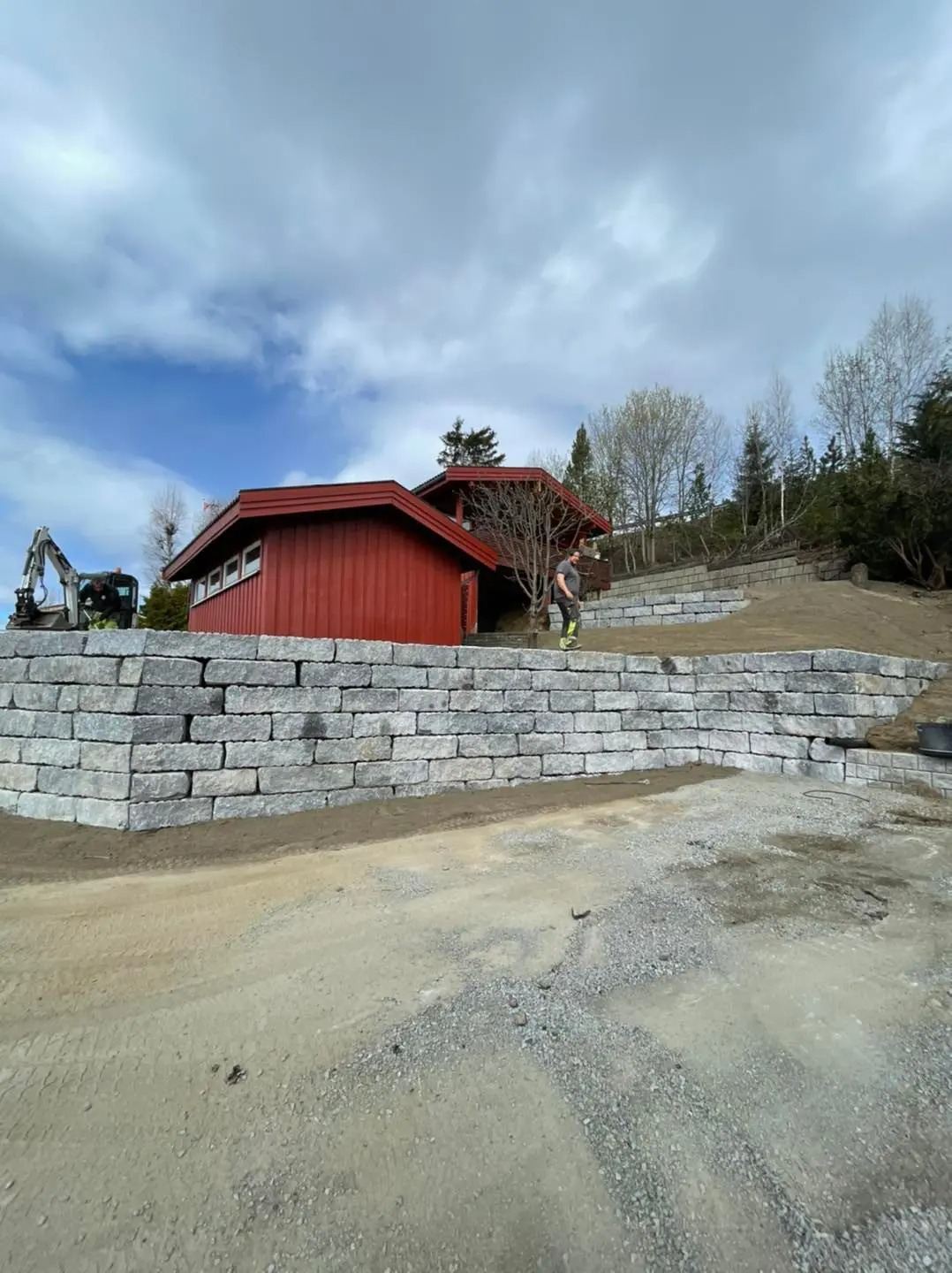 Ferdig natursteinsmur foran rødt hus